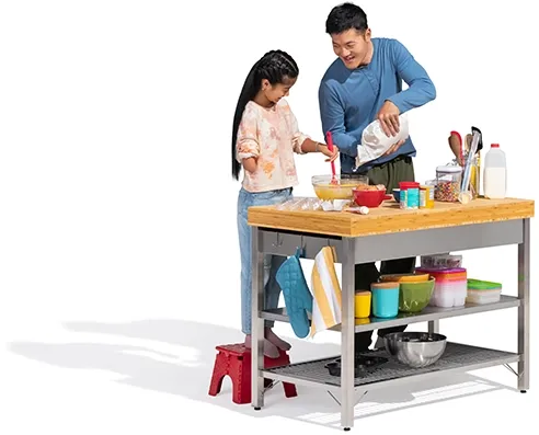 A father and daughter stir some batter at a free-standing kitchen counter